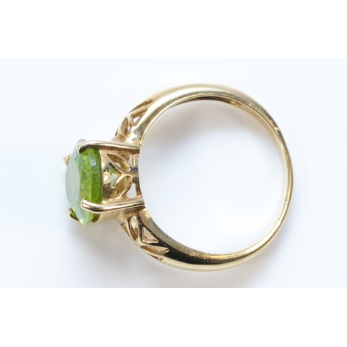 577 - A 9ct gold oval cut peridot dress ring with patterned shoulders, N, 3.4g