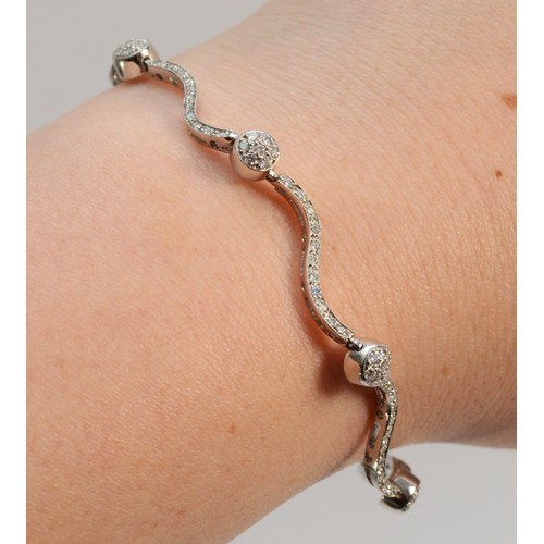 1334 - An Italian 18ct white gold, stamped 750, and brilliant cut diamond wavy link and ball bracelet, appr... 