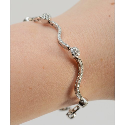 1334 - An Italian 18ct white gold, stamped 750, and brilliant cut diamond wavy link and ball bracelet, appr... 