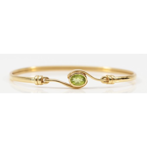 1365 - A 9ct gold and peridot bangle, 63 x 46mm, 7.1gm