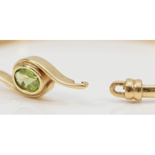 1365 - A 9ct gold and peridot bangle, 63 x 46mm, 7.1gm