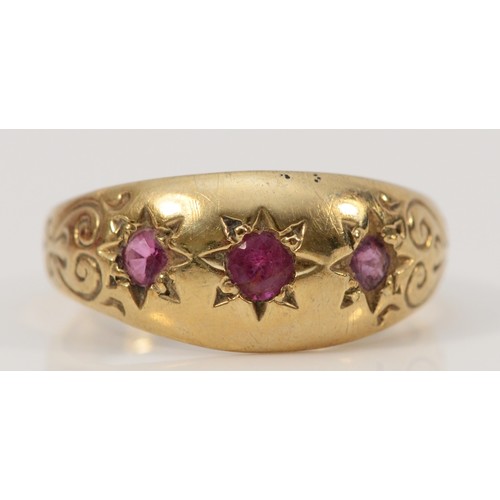 695 - A 9ct gold ruby three stone dress ring with engraved shoulders, O 1/2, 3g