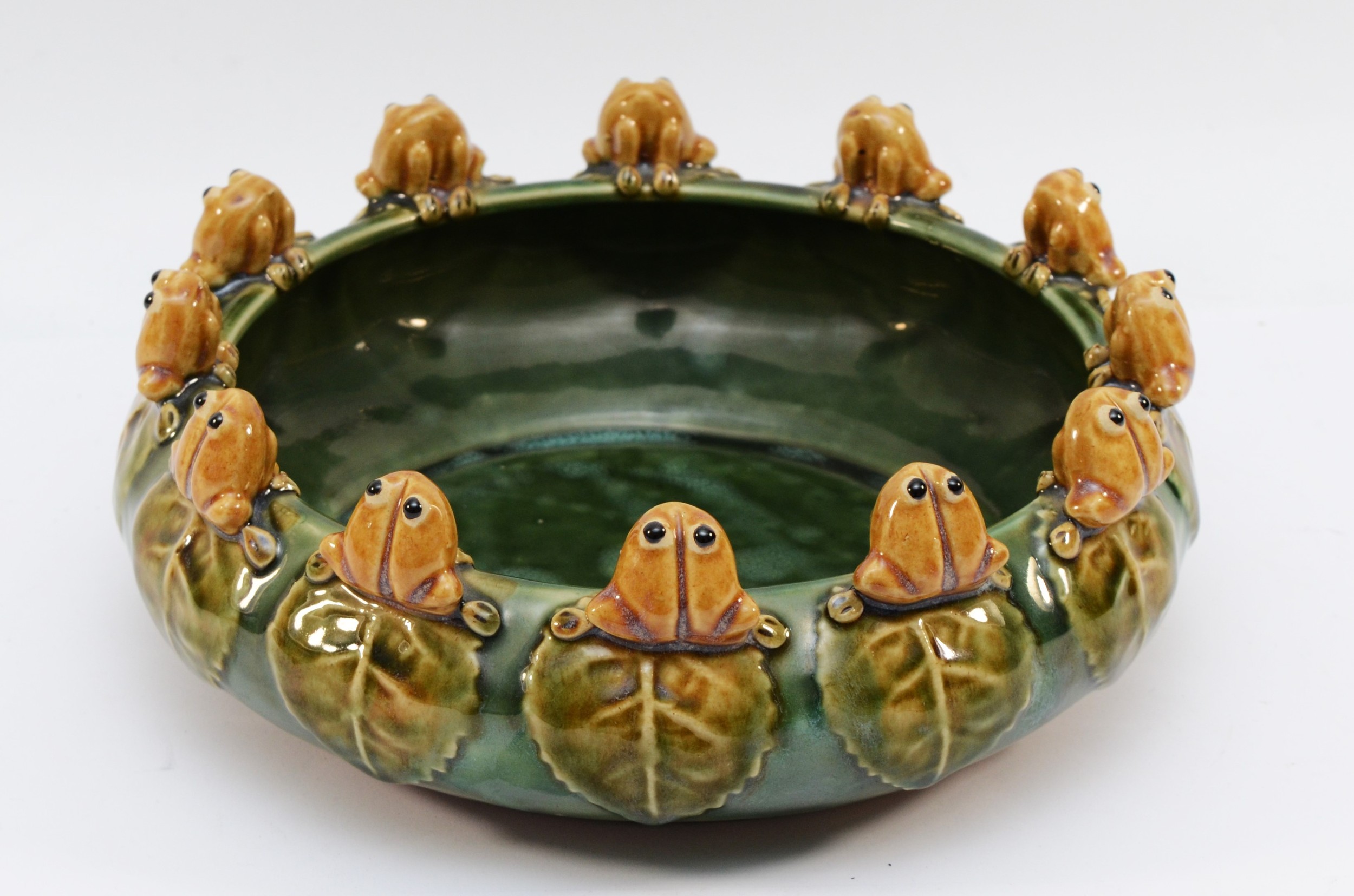 A Majolica bowl, the rim decorated with twelve ornamental frogs perched ...