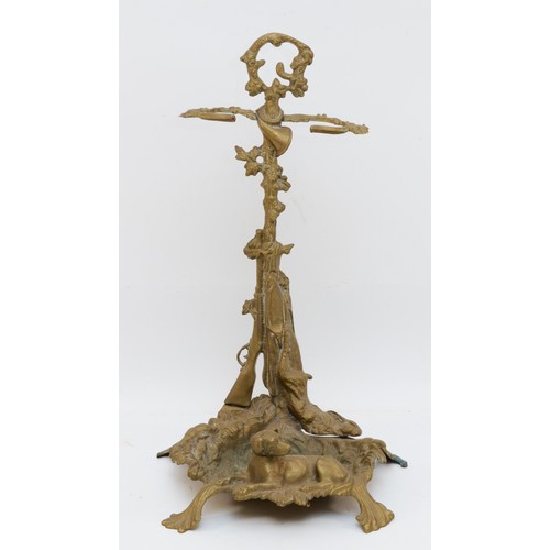 141 - A cast brass stick stand, with hunting horn, shotgun and hound, raised on a naturalistic ground, 56c... 