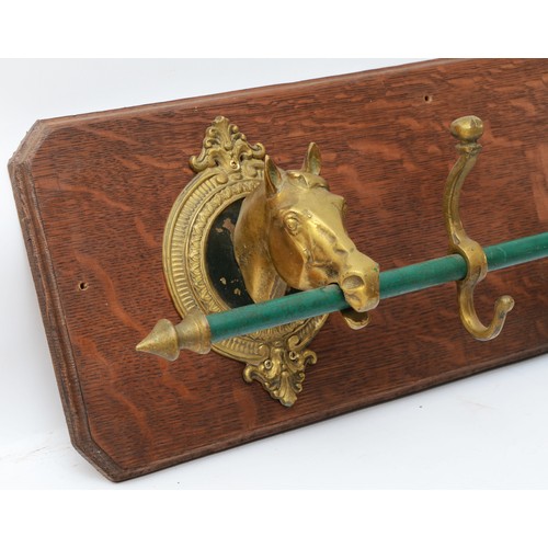 142 - A cast brass horses head coat rack, with four hooks, mounted on an oak board, length 108cm.