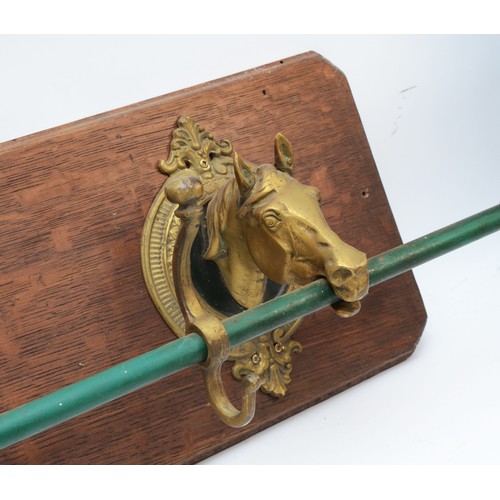 142 - A cast brass horses head coat rack, with four hooks, mounted on an oak board, length 108cm.