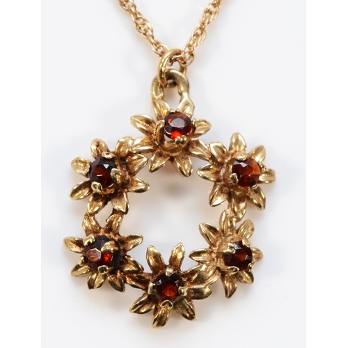 666 - A 9ct gold garnet floral wreath shaped pendant with chain, 17mm diameter, 3.6g