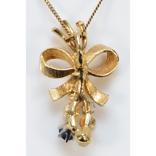 704 - A 9ct gold diamond, cultured pearl and sapphire bow shaped pendant with chain, 20mm total length, 1.... 