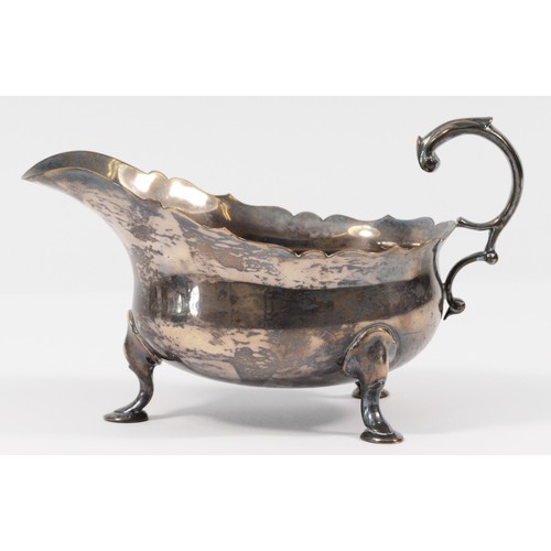 5 - A silver sauce boat, London 1933, with wavy edge and leaf capped flying scroll handle, 15.5cm, 160gm