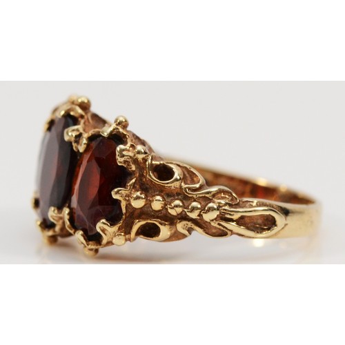 70 - A 9ct gold vintage garnet three stone ring with scroll patterned shoulders, cannot date due to resiz... 