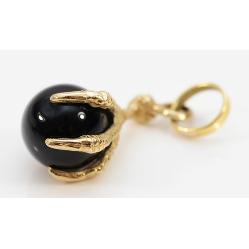 75 - A 9ct gold claw pendant holding an onyx ball, 10mm diameter onyx, 20mm total claw length, 2.7g