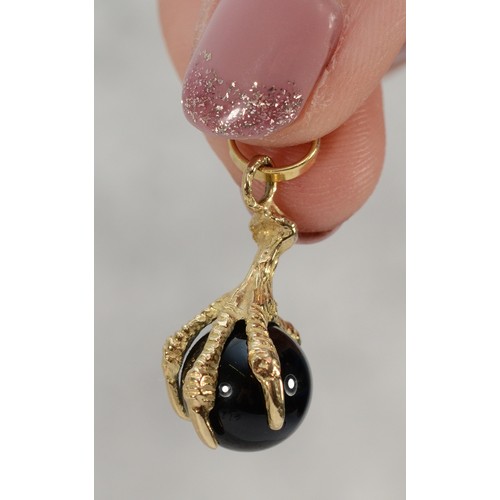 75 - A 9ct gold claw pendant holding an onyx ball, 10mm diameter onyx, 20mm total claw length, 2.7g