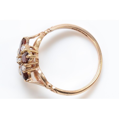 151 - A 9ct gold garnet and seed pearl floral cluster ring with patterned openwork shoulders, P 1/2, 2.5g