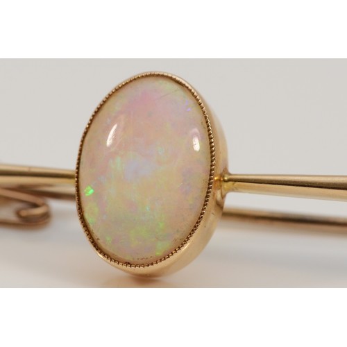 155 - An 18ct gold opal bar brooch, with safety chain, 14mm x 9mm opal, good colour play, 60mm across, 5g