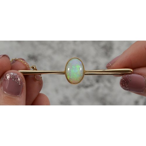 155 - An 18ct gold opal bar brooch, with safety chain, 14mm x 9mm opal, good colour play, 60mm across, 5g