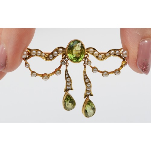 165 - A tested 15ct gold Edwardian peridot and seed pearl brooch with a 9ct pin, milgrain detailing surrou... 