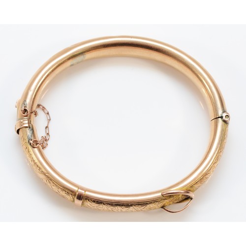 211 - An Edwardian 9ct rose gold hinged buckle bangle, Chester 1907, the front with engraved scroll decora... 