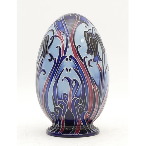 358 - A Moorcroft decorative egg, adorned with flowers and scrolling foliate, in blue and purple, dated 20... 