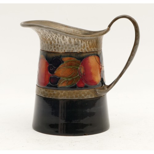 393 - A Moorcroft cream jug, in the pattern, 'Pomegranate', with a beaten pewter rim, manufactured between... 