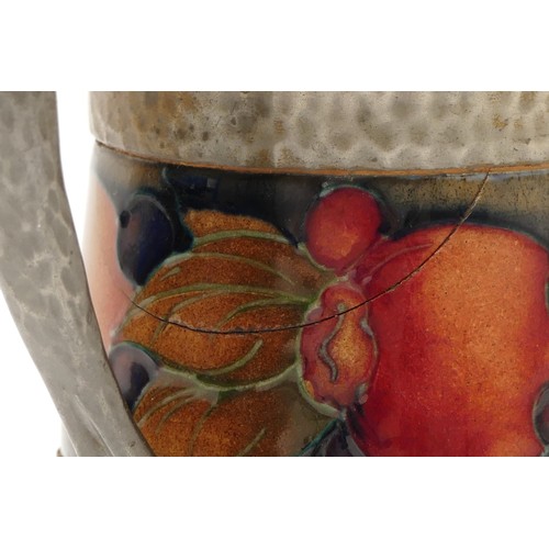 393 - A Moorcroft cream jug, in the pattern, 'Pomegranate', with a beaten pewter rim, manufactured between... 