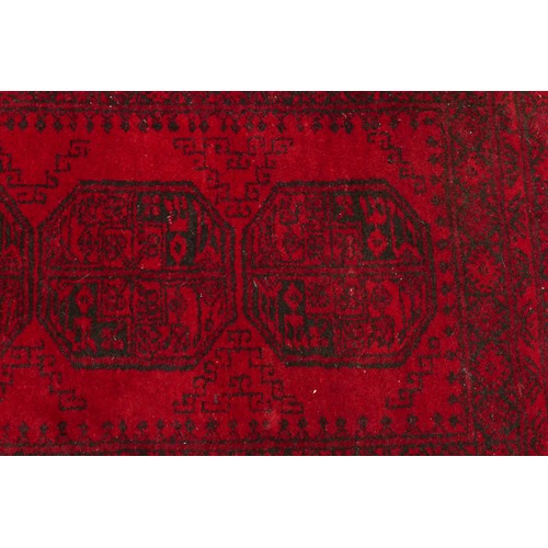 576 - Two rugs; one Afghan Belouch rug, with one row of three guls, enclosed by multiple borders and a fri... 