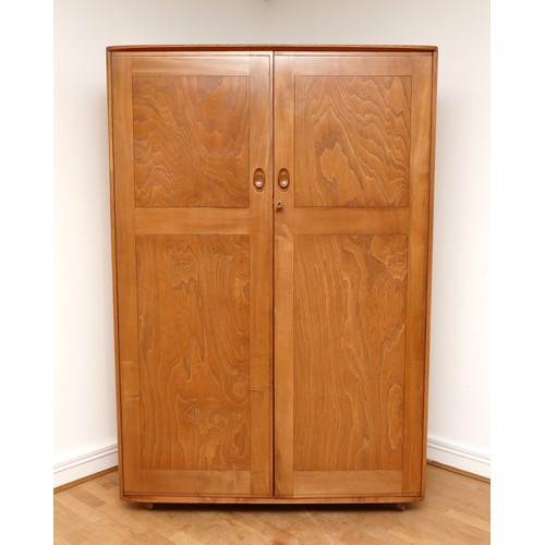 582 - A 1960s Ercol light elm 'Windsor' double door compactum wardrobe, enclosed by two fielded doors, the... 