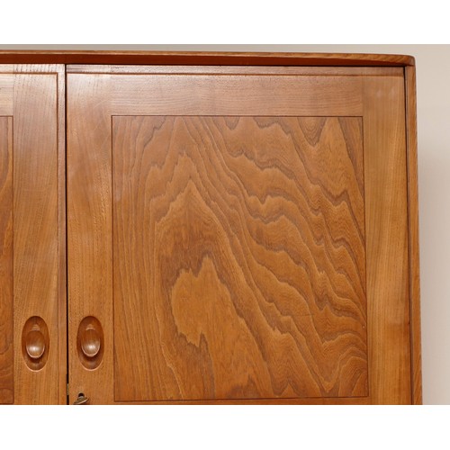 582 - A 1960s Ercol light elm 'Windsor' double door compactum wardrobe, enclosed by two fielded doors, the... 