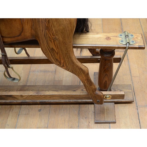 59 - An oak rocking horse, with chestnut mane and tail, on a trestle rocker frame supported by dual balus... 