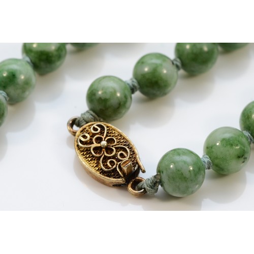 13 - A mottled jadeite bead necklace, 7mm beads, 60cm, silver gilt clasp