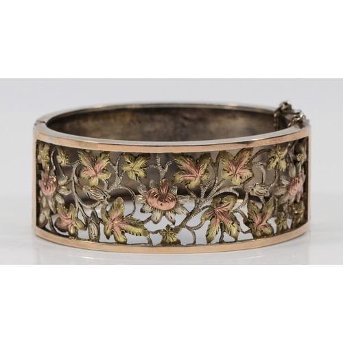 63 - A Victorian silver, two colour gold and cut work floral bangle, Birmingham 1883, with spring clasp, ... 