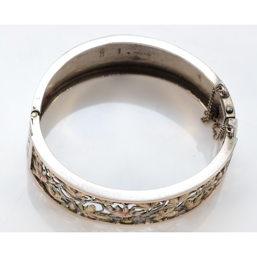 63 - A Victorian silver, two colour gold and cut work floral bangle, Birmingham 1883, with spring clasp, ... 