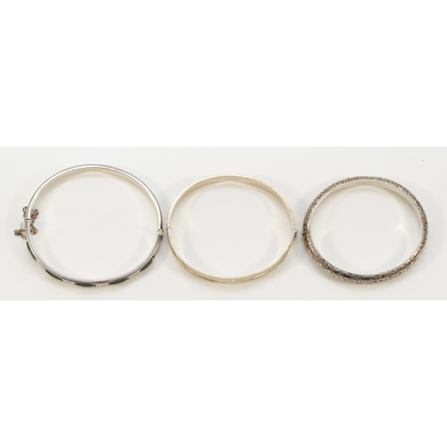 71 - A silver hinged bangle, exposed hallmarks London 1977, Jubilee duty mark, 62 x 52mm and two other si... 