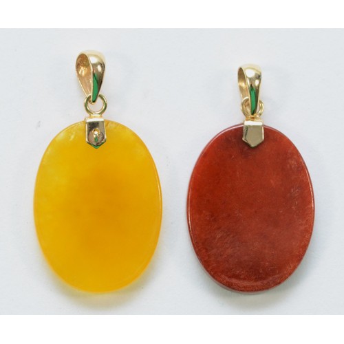 217 - Two 9ct gold pendants, a yellow and a red hardstone disc with a Chinese symbol, 4.3g