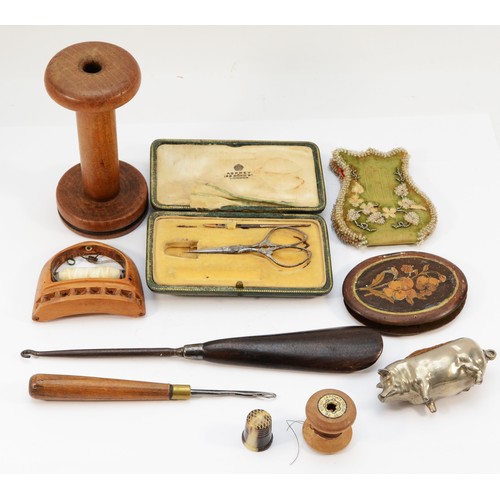 268 - An assortment of sewing equipment, to include, bobbins, thimble, antique French scissors, and pin cu... 