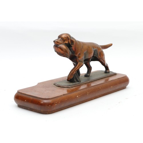 286 - A coppered cast metal model of a gun dog with catch, on a shaped mahogany plinth base. H10cm, W27cm.