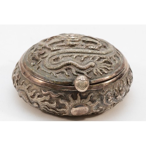 569 - A Chinese apparently unmarked silver circular box, having embossed decoration of the Chinese Dragon,... 