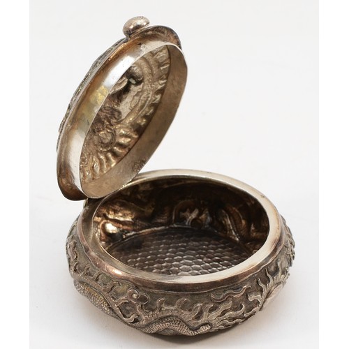 569 - A Chinese apparently unmarked silver circular box, having embossed decoration of the Chinese Dragon,... 