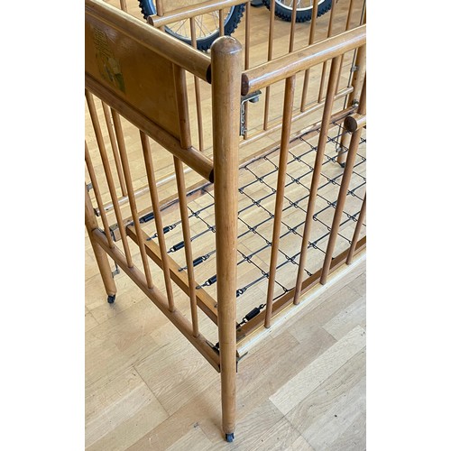 728 - A vintage beech childs cot, complete with sprung base on castors, 122x64cm.