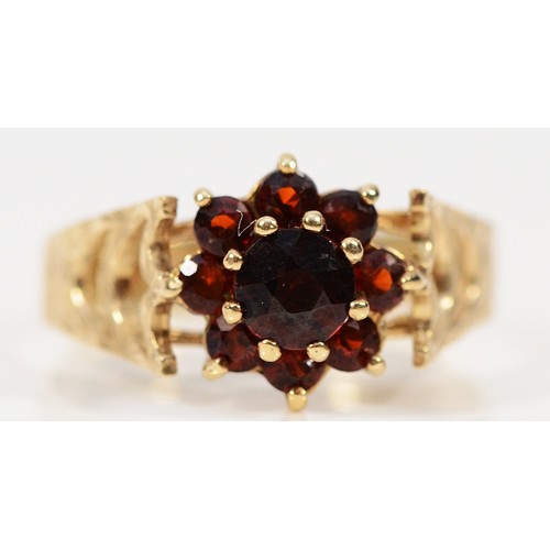 226 - A 9ct gold garnet floral cluster ring, with decorative shoulders, O 1/2, 2.3g