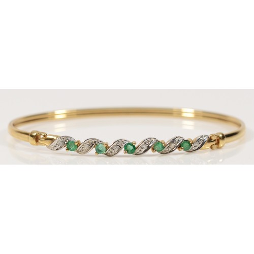 269 - A 9ct gold emerald and diamond twist bangle, hinge at the edge of the panel, 63mm internal, 4.7g