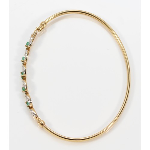 269 - A 9ct gold emerald and diamond twist bangle, hinge at the edge of the panel, 63mm internal, 4.7g