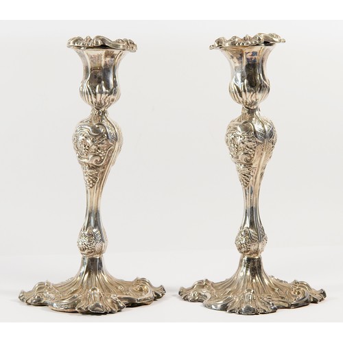 29 - A pair of silver fluted candlesticks, London 1963, with embossed decoration, 23cm, loaded.