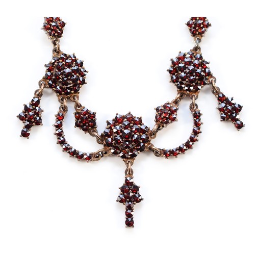 65 - An Austro-Hungarian gilt metal and Bohemian garnet triple cluster and swag necklace, the front 12cm,... 