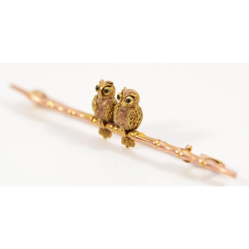 104 - An Edwardian 9ct yellow and rose gold brooch, in the form of two owls with green gemstone eyes sat o... 