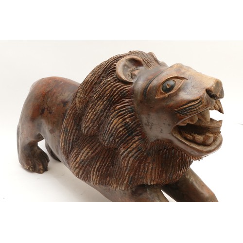 250 - A large probably Indian folk art naive carved wooden sculpture of an Asiatic lion, H36, L56cm.