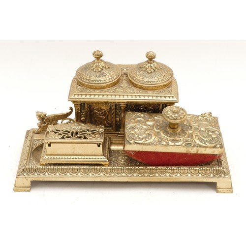 253 - A Victorian cast brass double inkstand, the central section with panels depicting an artist and a sc... 