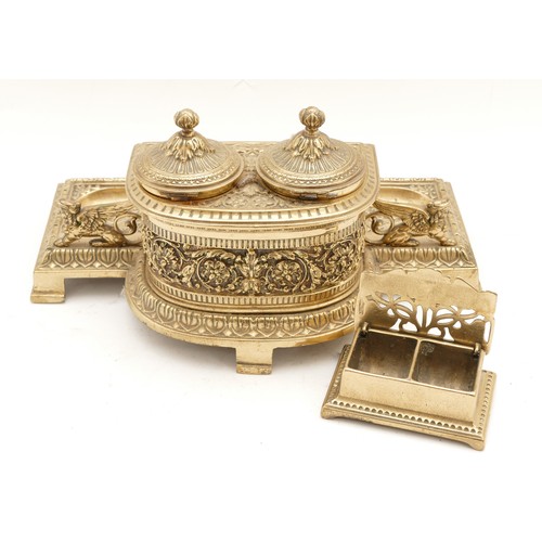 253 - A Victorian cast brass double inkstand, the central section with panels depicting an artist and a sc... 