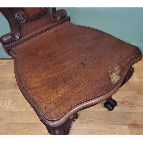 378 - A Victorian mahogany hall chair, the deeply carved scroll back with solid seat, raised on cariole le... 