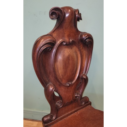 378 - A Victorian mahogany hall chair, the deeply carved scroll back with solid seat, raised on cariole le... 