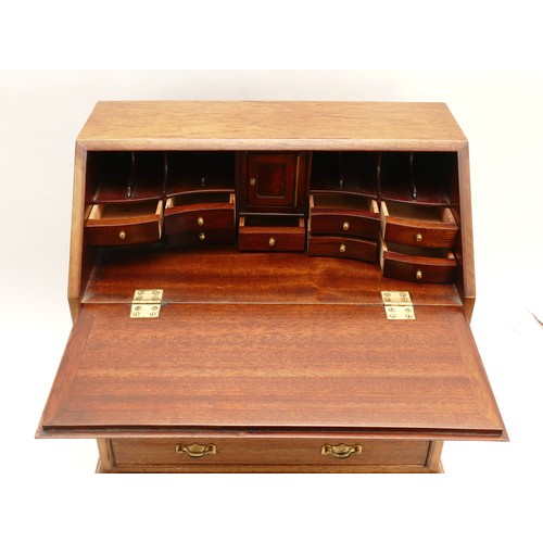 385 - A mahogany apprentice or miniature bureau, the fall flap opening to reveal pigeon holes, central cup... 